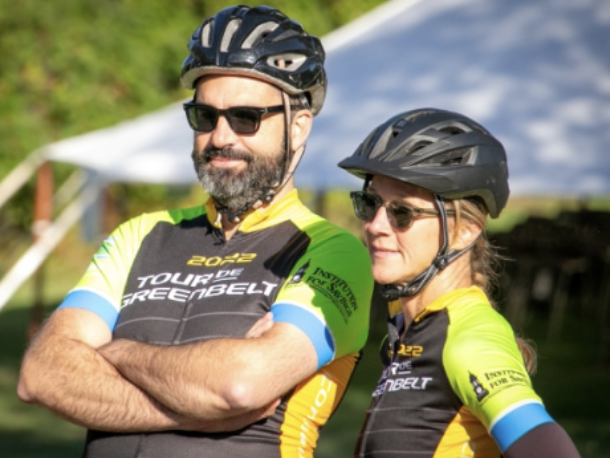 two cyclists off their bikes wearing helmets