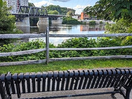 Iron bench looking out to an old rail fence, tress and the Merrimack River